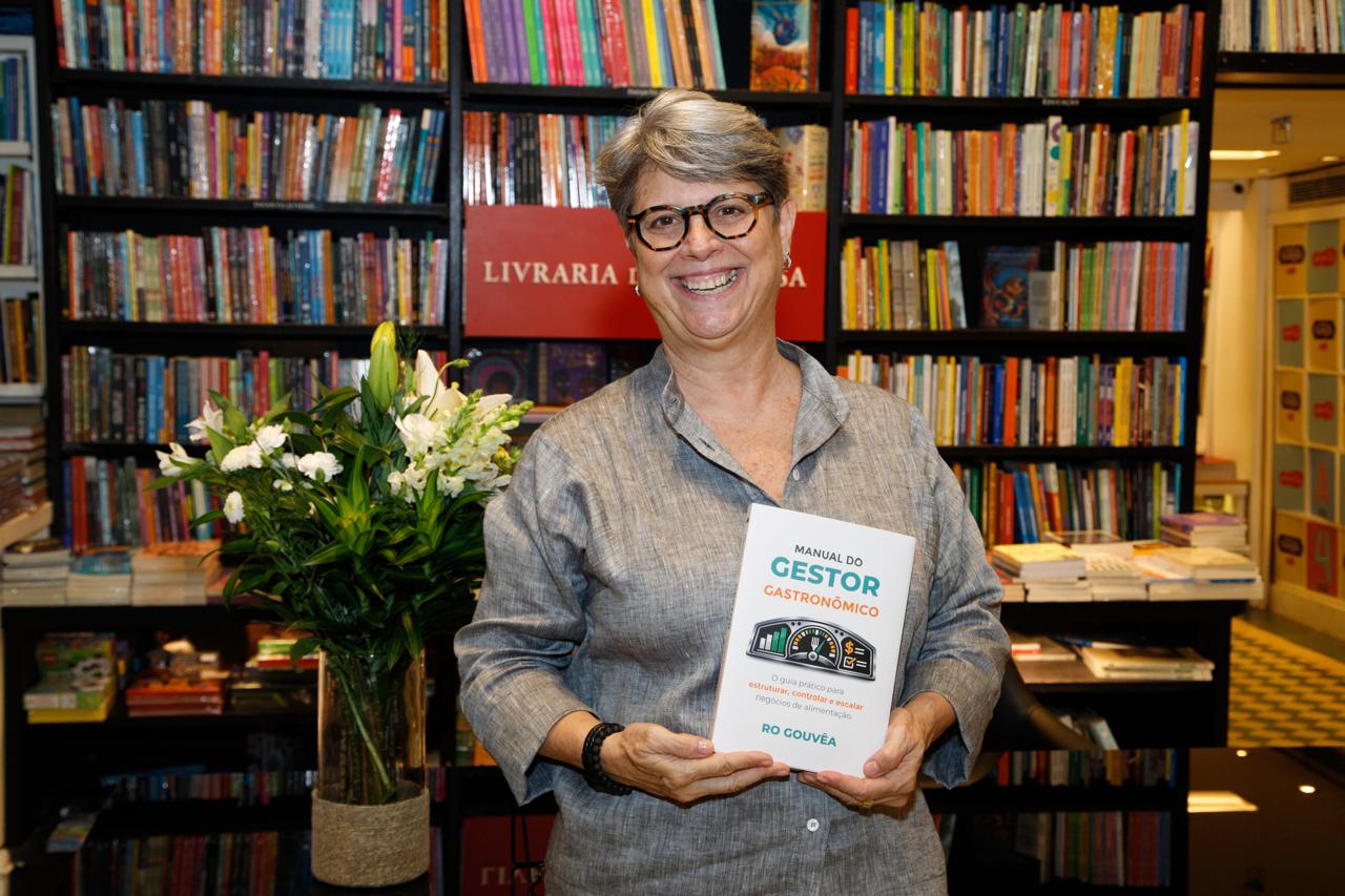 Ro Gouvêa segurando o livro Manual do Gestor Gastronômico na Livraria da Travessa