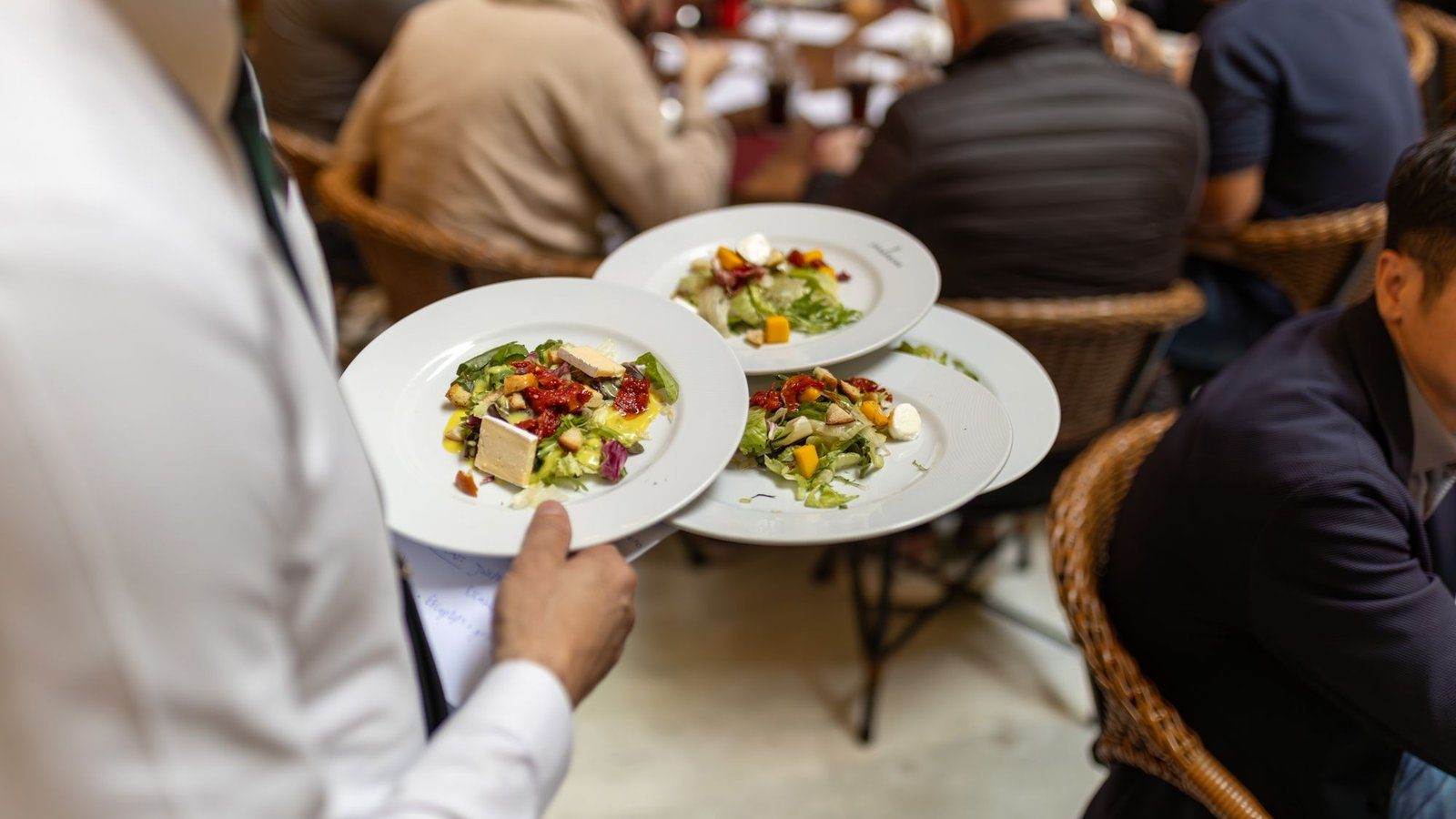 Garçom carrega pratos entre mesas cheias em um restaurante